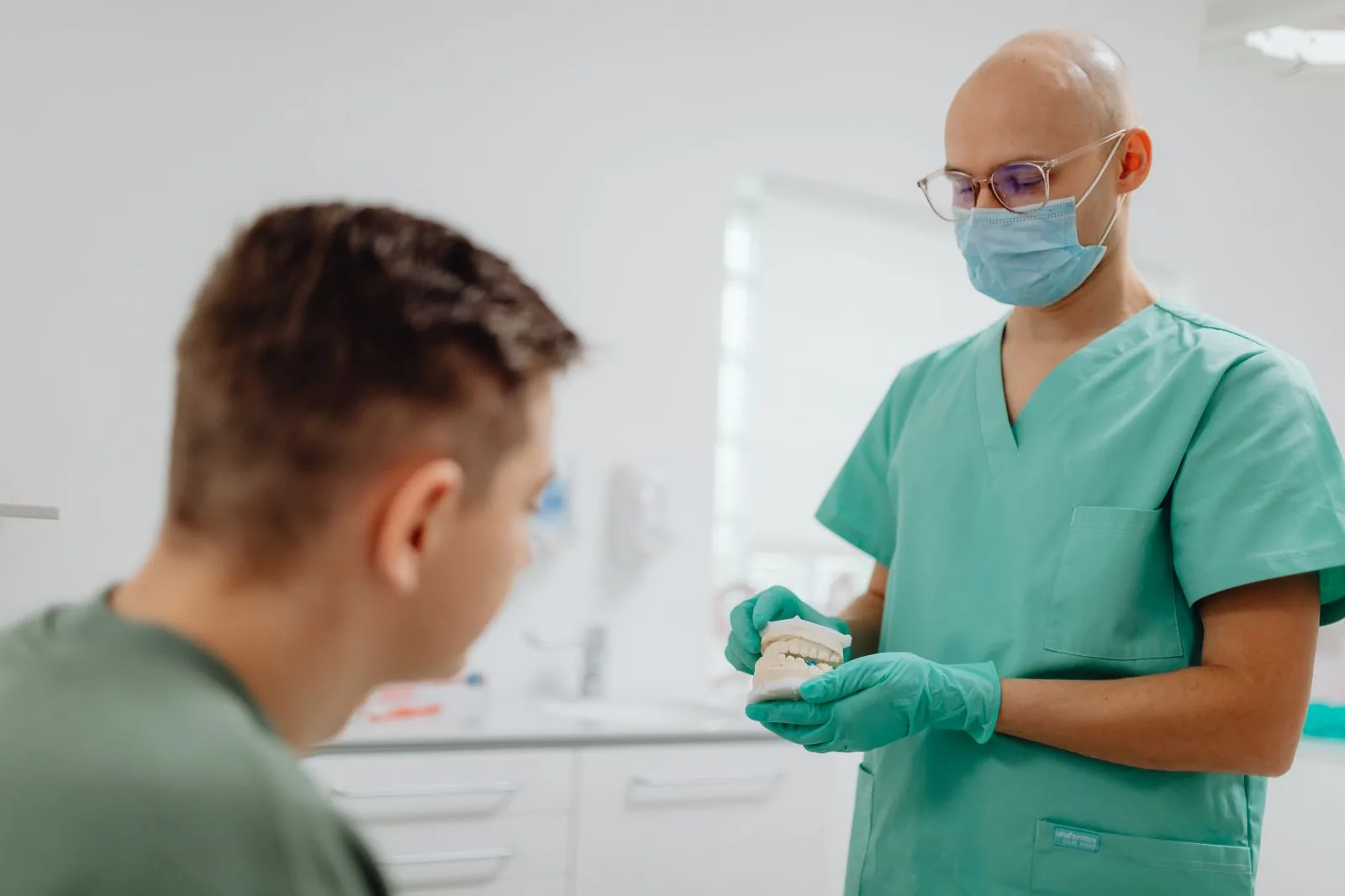 Medic ortodont care explică tratamentul pe un model dentar